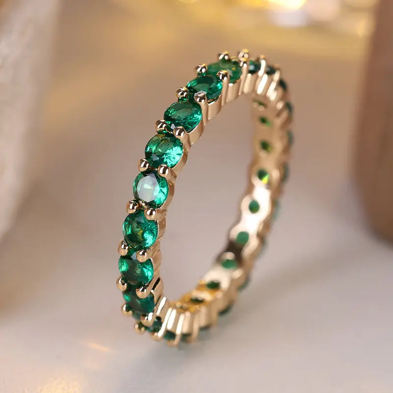 Gouden eternity ring met groene edelstenen