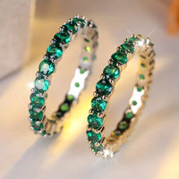 Gouden eternity ring met groene edelstenen