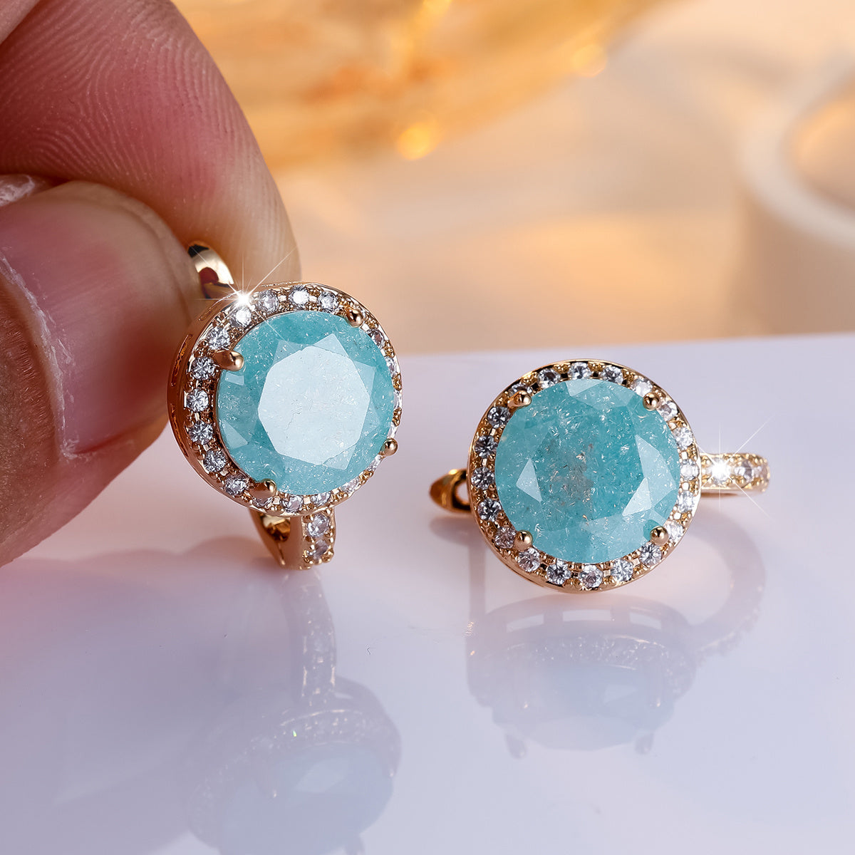 Gouden clip-oorbellen met ronde turquoise steen en zirkonia
