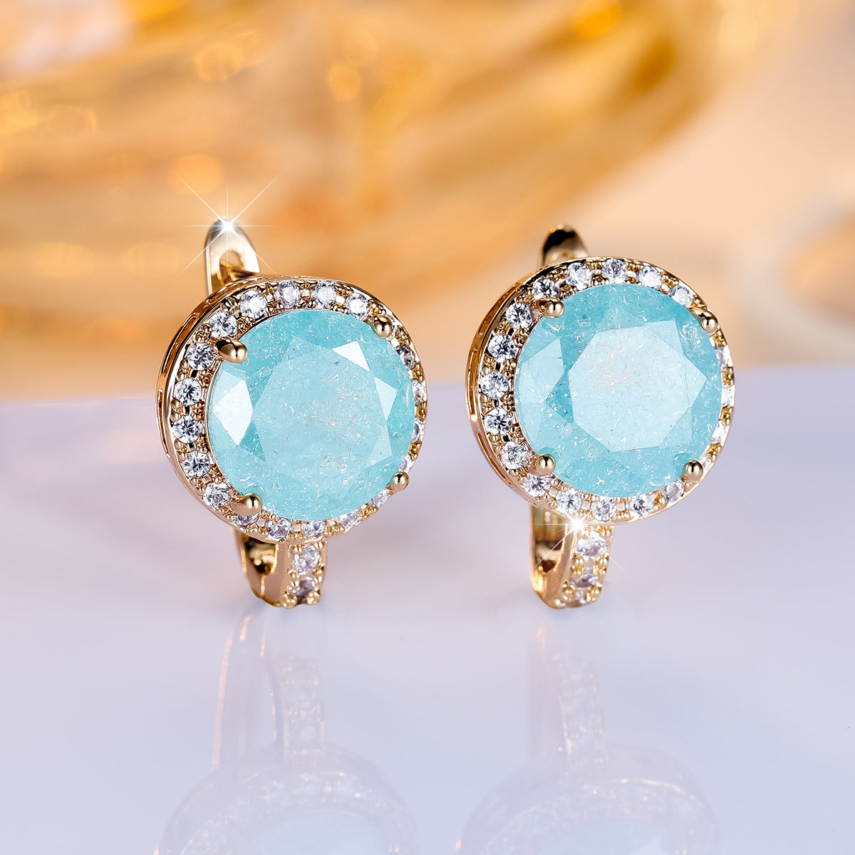 Gouden clip-oorbellen met ronde turquoise steen en zirkonia