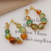 Gouden boho oorbellen met groene en oranje agaatkralen