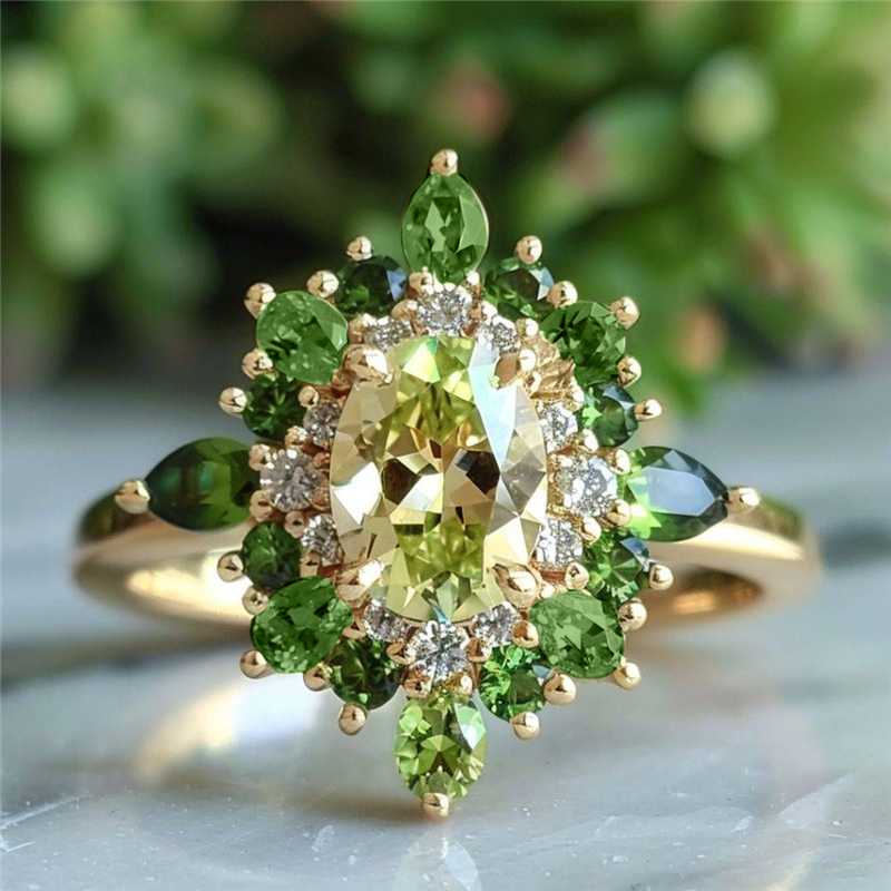 Gouden ring met groene edelstenen en halo