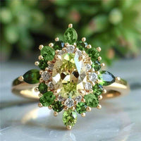 Gouden ring met groene edelstenen en halo