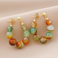 Gouden boho oorbellen met groene en oranje agaatkralen