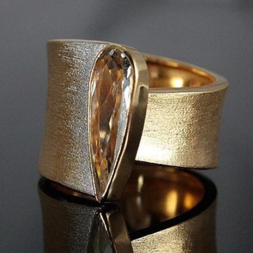 Gouden brede ring met peervormige champagne edelsteen