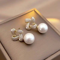 Gouden oorbellen met kristallen knoop en parelhanger