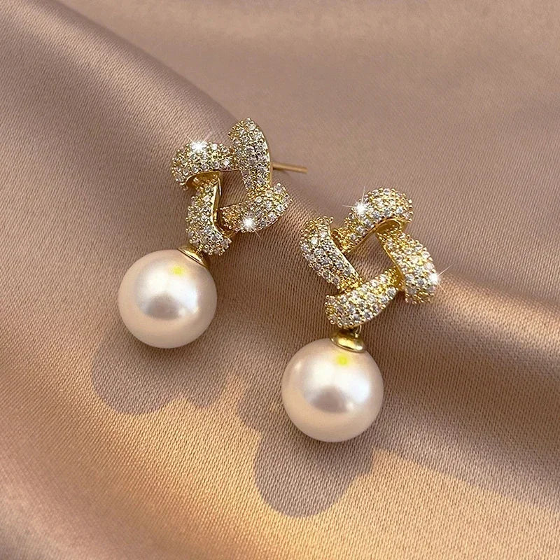 Gouden oorbellen met kristallen knoop en parelhanger