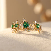 Gouden ring met groene edelstenen en blaadjes