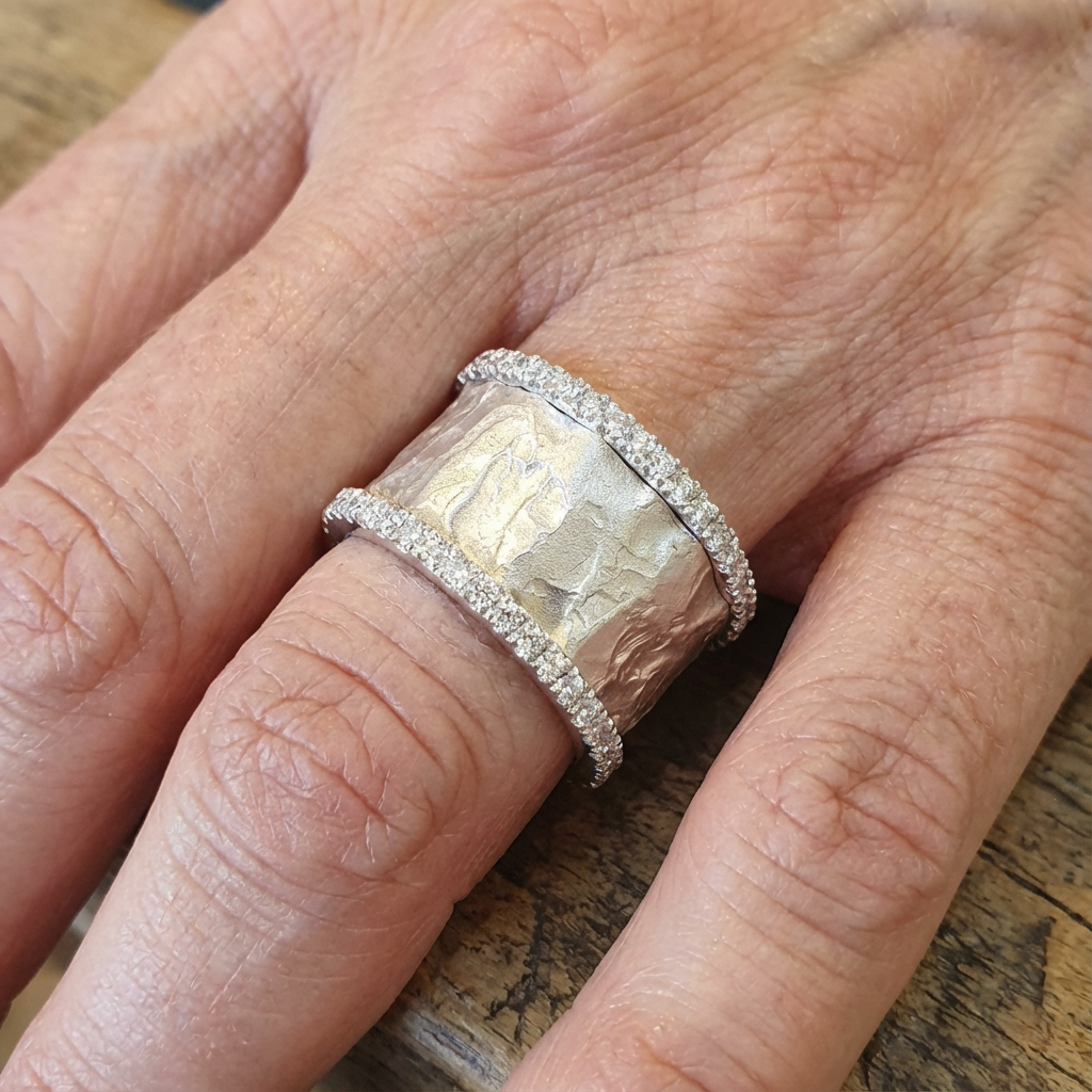 Brede gehamerde ringen in goud en zilver met zirkonia