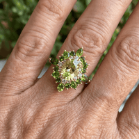 Gouden ring met groene edelstenen en halo