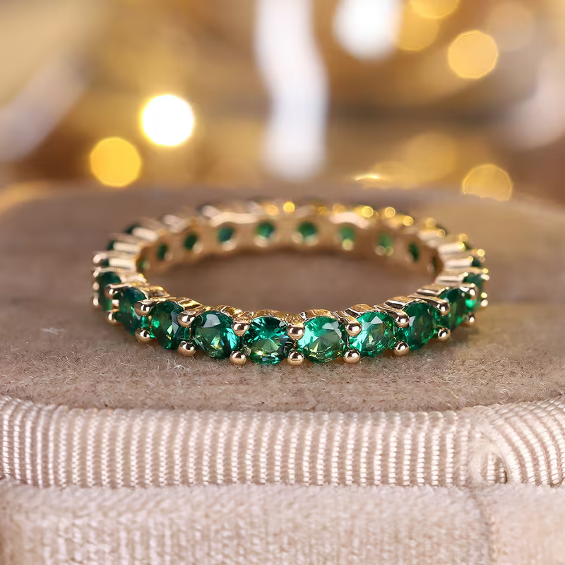 Gouden eternity-ring met groene edelstenen