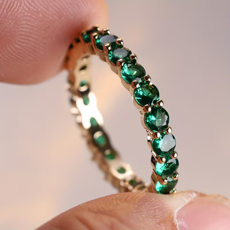 Gouden eternity-ring met groene edelstenen