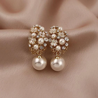 Gouden oorbellen met bloem van strass en parelhanger