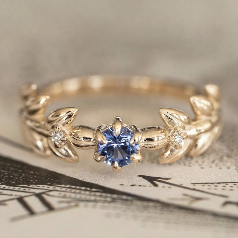 Gouden ring met blauwe steen en bladmotief