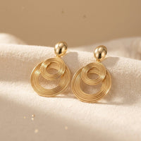 Gouden druppeloorbellen met gespiraliseerde ringen